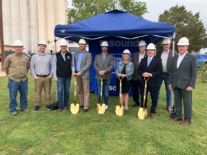 Men and women in the telecom industry holding shovels ready to break ground for a new fiber installation.