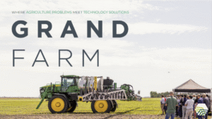 Farming machine equipment in field with people watching demonstration.